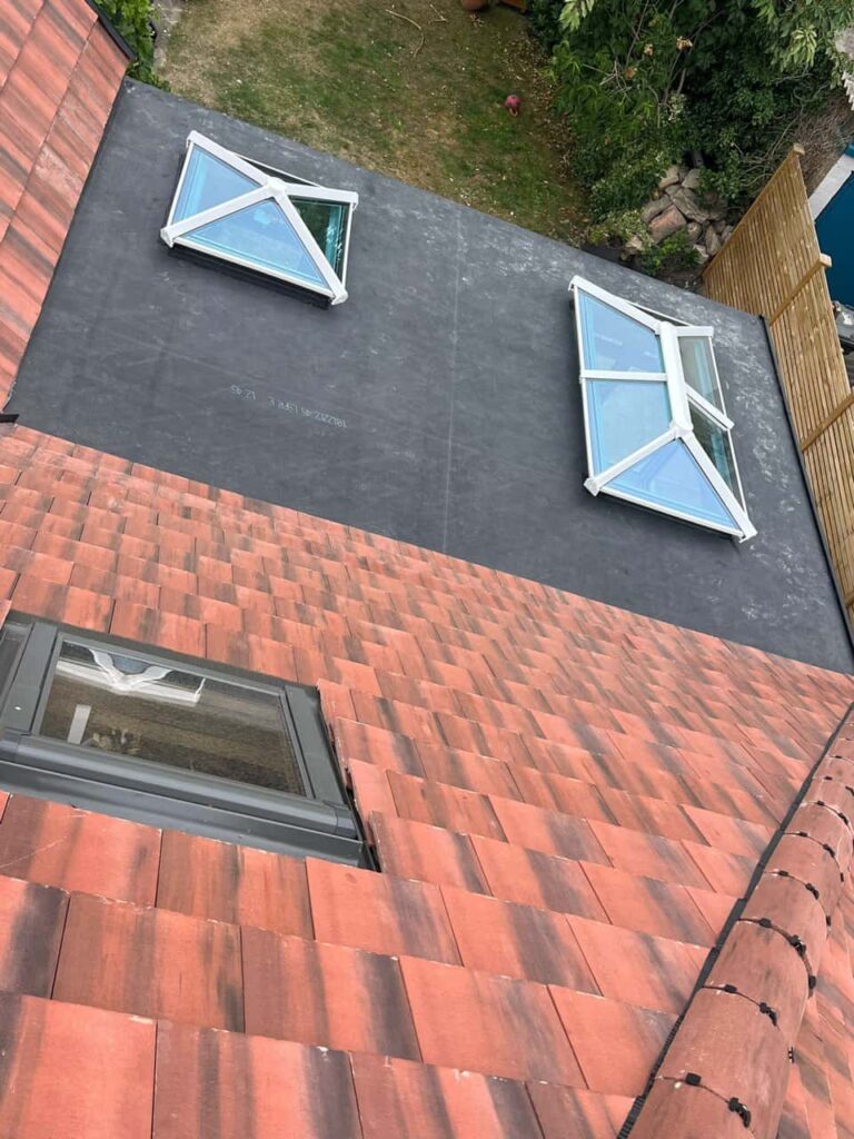 This is a photo taken from the roof ridge looking down a tiled pitched roof on to a flat roof. Works carried out by Newmarket Roofing Repairs